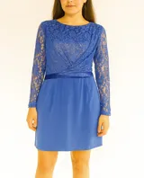 Vestido corto azul con encaje en la parte superior y mangas largas. Tiene corte a la cintura con una banda de satén y falda lisa.