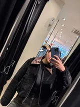 Chaqueta de pana negra con diseño acolchado, cierre frontal y cuello de solapa en cuero sintético marrón.