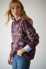 Buzo de tejido de punto en color marrón con un patrón ornamental floral en color celeste. Presenta cuello redondo, mangas largas y un corte holgado.