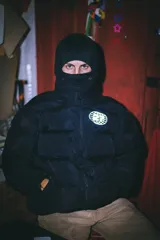 Campera puffer negra con capucha y cierre frontal. Tiene un logo estampado en el pecho.