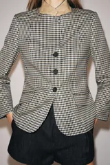Blazer de corte estructurado con estampado de cuadros vichy en tonos neutros. Presenta cuello mao en color beige, cierre frontal con botones oscuros y bolsillos con solapa en el delantero.