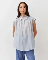 Camisa celeste sin mangas con diseño a rayas sutiles, de corte amplio y silueta fluida. Presenta cuello camisero y cierre frontal parcial con botones.
