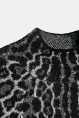 Jersey de punto con estampado animal jacquard en tonos gris y negro, caracterizado por su cuello subido y mangas anchas de corte holgado.