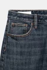 Jeans de mezclilla de tiro bajo y corte recto, con diseño de cinco bolsillos, trabillas para cinturón y dobladillo con vuelta ancha. Presenta un lavado azul medio con efecto desgastado.