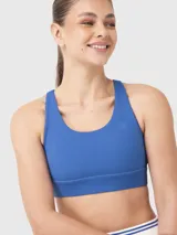 Top deportivo de color azul con diseño de espalda nadadora y banda elástica inferior. Presenta un pequeño logo bordado en el pecho.