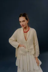 Chaqueta de lino color beige, de calce relajado, con escote en V, cierre frontal con botones y bolsillos frontales aplicados.