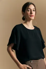 Top negro de corte relajado con escote redondo y mangas cortas con caída fluida y volumen sutil.