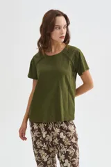 Remera de algodón verde militar, de manga corta y corte holgado, con cuello redondo a la base y detalle de cinta perforada en los hombros.