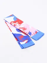 Pañuelo de seda o material similar, estampado con patrón de leopardo en tonos marrones y negros, con borde liso negro.