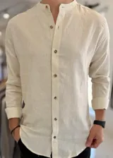 Camisa de lino color beige, de manga larga, con cuello mao y cierre frontal de botones.