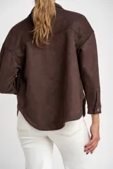 Sobrecamisa de gamuza sintética en color marrón chocolate, con corte oversize, cuello camisero, cierre frontal con botones y bolsillos frontales tipo parche.