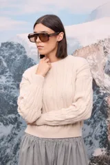 Buzo de punto grueso en color beige, con diseño de trenzas verticales y cuello redondo.