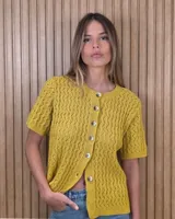 Cardigan de punto calado color mostaza, de manga corta, con cuello redondo y cierre frontal de botones.