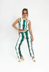 Pantalón de corte recto y tiro medio-alto, confeccionado en tela crepé con estampado geométrico de bloques en tonos verde, lila y blanco. Cuenta con pretina, cierre frontal y botón.