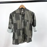Camisa de hombre con cuello mao y estampado de arabescos en tonos verde, gris y negro. Mangas largas con puños enrollados.