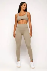 Conjunto deportivo de mujer color beige, compuesto por un top de tirantes anchos con escote curvado y calza de tiro alto con diseño sin costuras frontales.