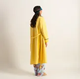 Bata clásica amarilla con textura capitoné y ribete verde en cuello, solapa, puños y cinturón.