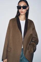 Blazer oversize de Zara Woman Collection confeccionado en mezcla de lana, con cuello sin solapa, manga larga y cierre frontal con botón. Presenta bolsillos delanteros con solapa.