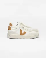 Championes Veja modelo V-90, de diseño urbano en color blanco con detalles en gamuza color tostado en el logo lateral, talón y puntera. Presentan perforaciones en la parte delantera y suela de goma al tono.
