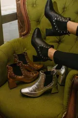 Botas cortas negras de cuero con elásticos laterales, taco cuadrado y apliques de tachas plateadas.