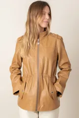 Campera confeccionada 100% en cuero ovino color arena. Estilo cazadora, con cinta ajustable oculta en cintura para entallar, bolsillos a los costados y charreteras en hombros.