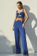 Conjunto de dos piezas color azul eléctrico, compuesto por un top corto con escote corazón y detalle de argolla central, y un pantalón de tiro alto con aberturas laterales en la cintura decoradas con argollas metálicas.