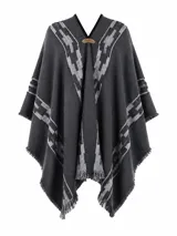 Poncho color beige con diseño de guardas geométricas en tonos grises y negros, detalles de flecos en los bordes y escote en V con aplique de cuero sintético con el logo de la marca.