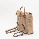 Mochila de diseño bicolor en tonos crema y beige, con cierre superior, asa de mano y detalle de colgante con cuentas coloridas.