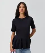 Blusa femenina de manga corta y cuello redondo, color negro, confeccionada en algodón. Presenta un corte levemente entallado con recorte en la cintura y un volado estilo peplum en el bajo.