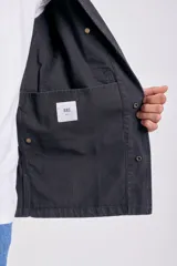 Campera de color negro para hombre, con cuello camisero, cierre frontal de botones y bolsillos aplicados en el frente.