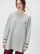 Sweater gris de punto con diseño de rombos, cuello redondo y mangas largas. Cuenta con puños largos acanalados con rayas horizontales en color verde militar y un pequeño logo bordado en el pecho.