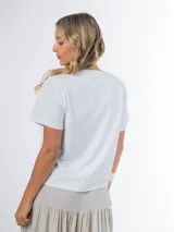 Remera blanca de tejido liviano con aplique de flor de crochet en el frente.