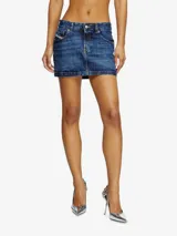 Falda corta de denim azul oscuro, con lavado desgastado y tiro bajo. Presenta cinco bolsillos y cierre frontal con botón y cremallera.