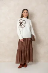 Buzo de tejido de punto color blanco, con cuello alto acanalado y mangas largas con puños ajustados. Presenta un diseño de flor grande en color chocolate aplicado en el frente.