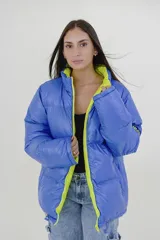 Campera puffer reversible de corte holgado, con cuello alto y cierre frontal. Un lado es de color azul vibrante con detalles en verde lima en el cierre y el interior, y el otro lado es de color negro.