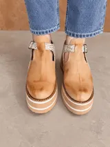 Guillerminas de cuero marrón chocolate, con detalles en animal print y textura dorada metalizada. Presentan una tira con hebilla metálica en el empeine, aberturas laterales y suela de plataforma corrida con franjas en contraste.