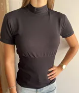 Polera negra de manga corta con cuello alto y corte ajustado.