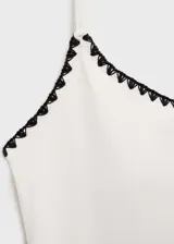 Malla enteriza de color blanco con ribetes en contraste de color negro. Presenta un diseño de espalda descubierta, cuello escotado y tirantes finos.