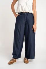 Pantalón wide leg de tiro medio y corte holgado, color azul marino, con pinzas en la parte frontal, bolsillos laterales y cierre con botón.