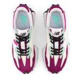 Championes New Balance modelo 327, de dama, con diseño multicolor en fucsia, morado, blanco, verde menta y negro. Presentan una entresuela ensanchada, empeine de ante y malla, y una marca "N" de gran tamaño aplicada asimétricamente. La suela tiene un relieve inspirado en el trail.