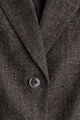 Blazer largo de botonadura sencilla con solapas de muesca, hombreras, pinzas en la cintura y bolsillos delanteros ribeteados. Presenta mangas tres cuartos con diseño remangado y forro interior.