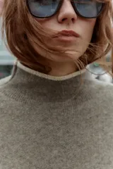 Jersey de punto con cuello subido y manga larga, de corte holgado. Presenta detalles de vivos en color crema en el cuello, puños y costuras de las mangas, contrastando con el tono marrón jaspeado de la prenda.