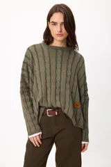 Sweater de punto con diseño de rayas verticales en relieve y textura trenzada, color terracota y beige. Presenta cuello redondo, corte holgado y diseño cropped.
