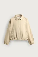 Cazadora cropped fit de algodón color beige, con cuello solapa, manga larga y cierre frontal de cremallera. Cuenta con bolsillos de vivo en la cadera, acabados elásticos y detalle de bordado a tono en el pecho.