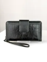 Billetera grande de cuero negro con textura de reptil y detalles de costuras en contraste. Cuenta con solapa frontal con cierre magnético y correa de muñeca extraíble.