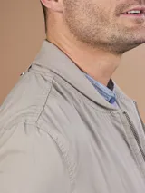 Campera bomber gris claro con cierre frontal y bolsillos laterales.