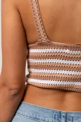 Top corto de tejido de punto crochet, con tirantes anchos y escote en V pronunciado. Presenta un diseño a rayas horizontales y en chevron en el busto, combinando color marrón claro/camel y blanco.