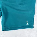 Short deportivo azul petróleo con cintura elástica ajustable con cordón y bolsillos laterales.