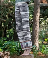 Pantalón tejido a mano en lana merino de corte recto, con diseño de rayas y guarda bordada con motivos florales y geométricos en el bajo.