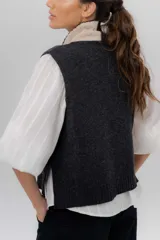 Chaleco de punto de lambswool color marrón, con cierre frontal y cuello alto en combinación de color gris y negro.